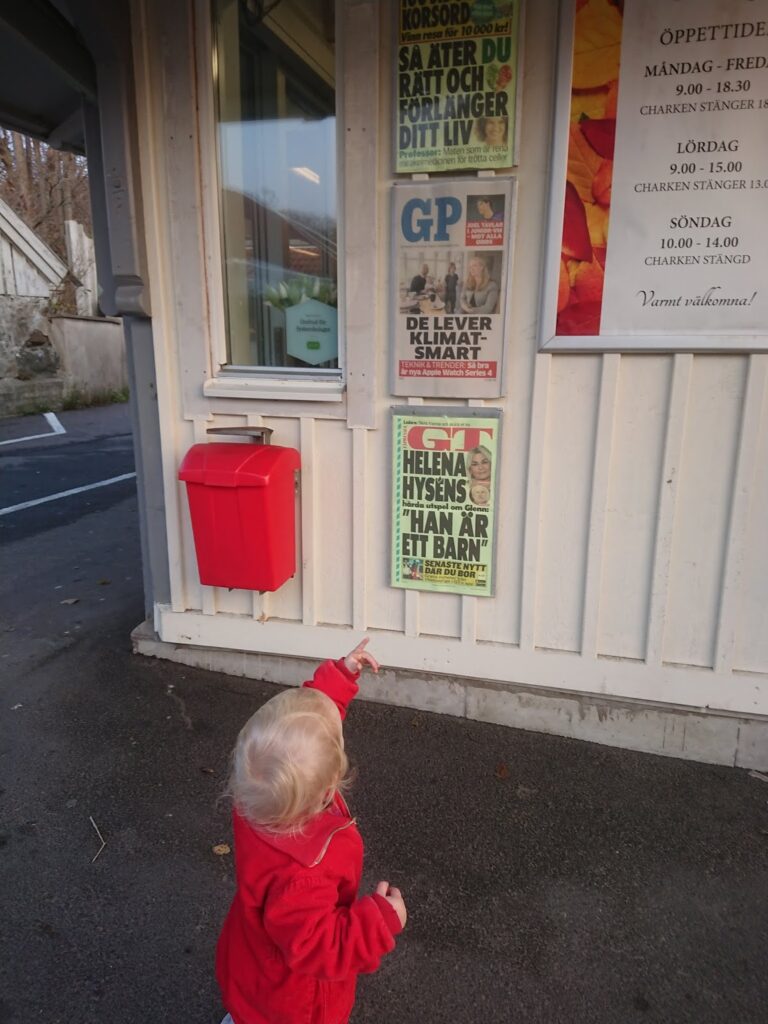 Lilla Eila tittar på en löpsedel med sin familj på
